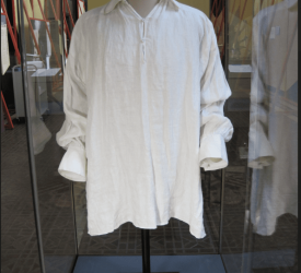 White historical shirt displayed on a mannequin inside a glass museum case.